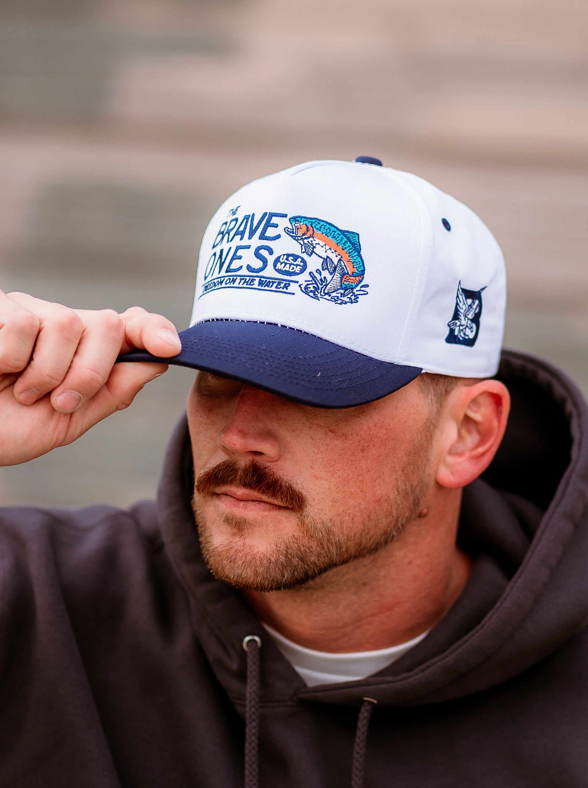 Close-up of The Big Bow Hat featuring embroidered rainbow trout and water detail